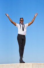 Androgynous businessperson celebrating success with open arms under blue sky