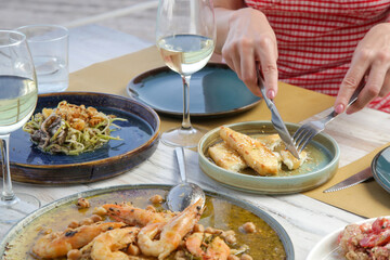 Young woman having dinner in the Mediterranean restaurant. Various dishes served on the table.	