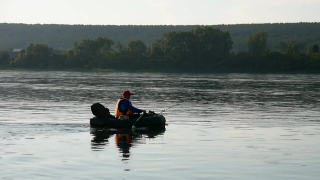 One elderly fisherman in a boat rowing on the river