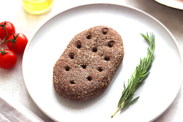 a piece of black bread and rosemary on a plate