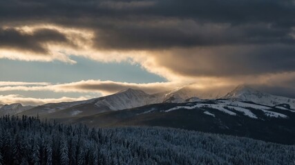 A stunning winter landscape featuring snow-capped mountains under dramatic clouds and soft sunlight.