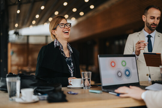 Businesspeople enjoy collaborative discussion in an outdoor setting, embracing creativity and teamwork. The atmosphere appears light and joyful, depicting successful engagement in a professional area.