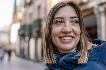 Young woman smiling in a city street looking away