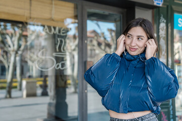 Young woman listening music with earphones outdoors and smiling © Jorge