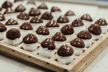 Marshmallow sweets in the form of mushroom in wooden tray on industry. Brown-white boletus.