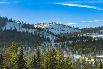 mountain range, forested mountains with picturesque sky, norwegian mountains in snow, snow-covered pines and firs, cloudy sky, 