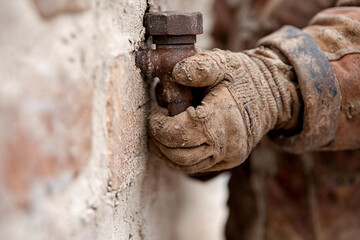Hands using a wrench to tighten bolts on a brick wall during a construction project
