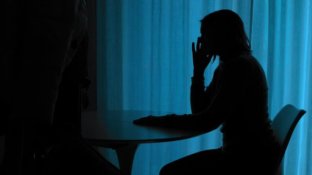 The silhouette of a girl stands alone at night, expressing solitude and sorrow in the darkness.