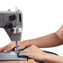 Close-up of hands sewing fabric with a sewing machine on a wooden table.