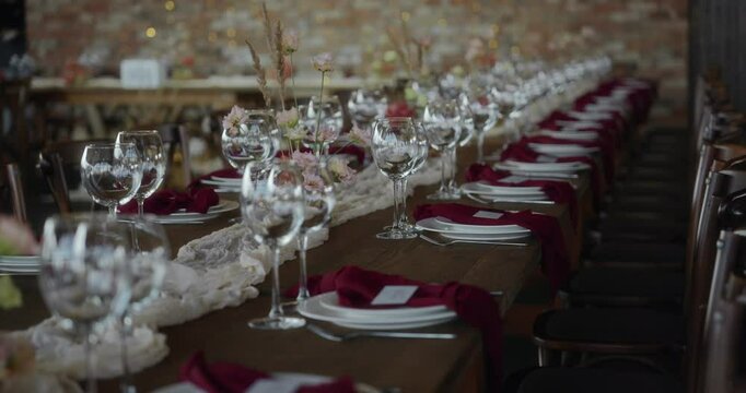 An atmospheric shot. The prospect of a long dining table decorated in rustic style and served with beautiful dishes. A festive table at a wedding dinner or other celebration. High quality 4k footage