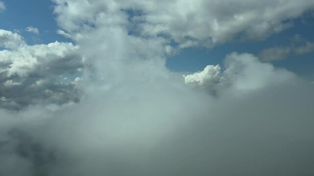 An immersive view through the pilot&rsquo;s eyes from a jet cockpit while flying through ethereal clouds under a blue sky. An aerial footage taken from a jet cokpit.