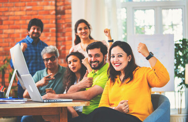 Young Indian entrepreneurs cheerfully celebrating success at a startup office after hard work