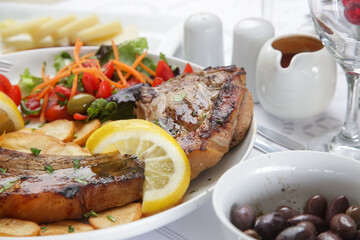 Pork chop with rib bone served with potato and green salad	