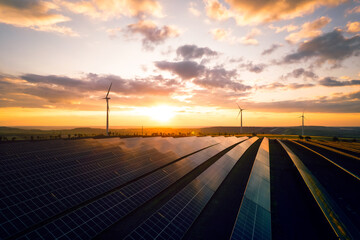 Windmill turbines and solar panels generating green energy electric.Clean and environmental technology.Photovoltaic power station and wind turbines at sunset.
