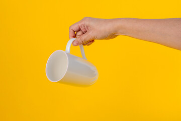 Hand and white cup isolated on yellow background