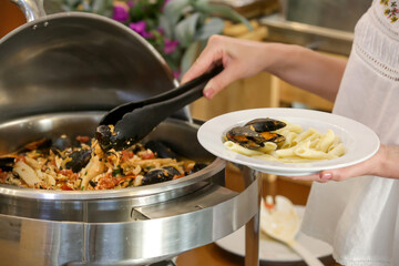 Woman taking food from a buffet line	