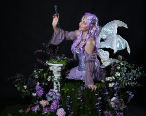 full length portrait of pretty female model wearing fantasy elf costume with fairy wings and purple...