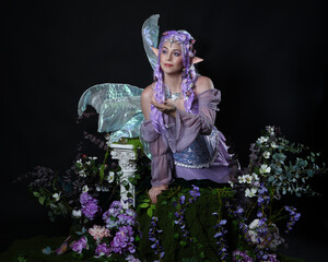 full length portrait of pretty female model wearing fantasy elf costume with fairy wings and purple...