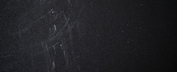 Dark textured surface featuring chalk residue and scratches, showcasing signs of wear and age, creating a gritty, panorama banner abstract background