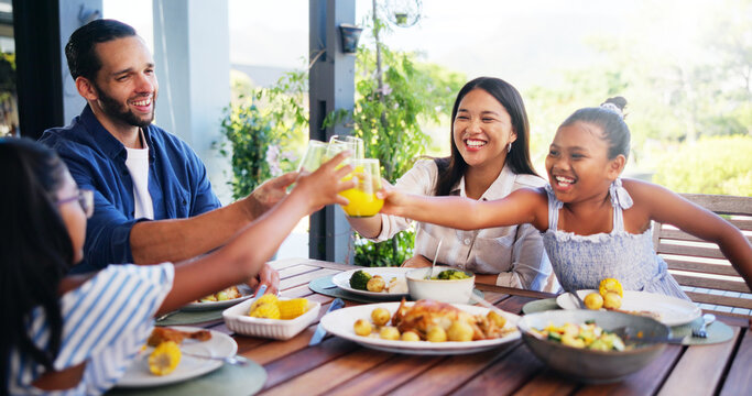 Happy family, lunch and cheers with juice for celebration at outdoor patio with love, care and bonding together. Mom, dad and kids toast with drink glass for food or healthy meal with parents at home