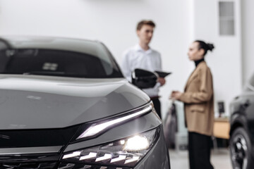 A car dealer in a modern car dealership advises a customer on buying or leasing a new car. The...