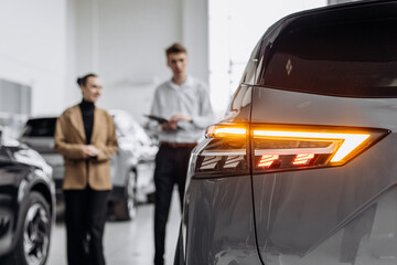 A car dealer in a modern car dealership advises a customer on buying or leasing a new car. The...