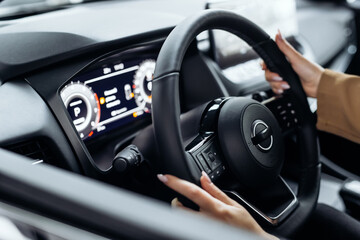 A woman's hands rest on the steering wheel of a modern automobile. The confidence and ambition of the concept is reflected in the choice of a new prestige car.