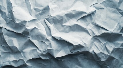 Fototapeta premium Crumpled blue paper texture showcasing intricate folds and shadows, ideal for backgrounds or artistic projects