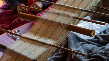 Elderly hand weaving fabric on a traditional wooden loom