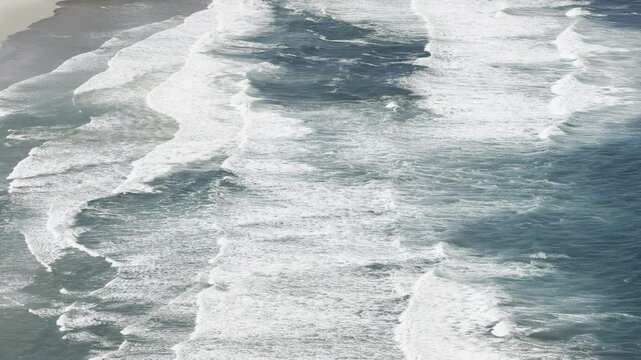 Powerful waves of pacific ocean crashing on a wild sandy beach seen from above. Sandfly bay, Otago Peninsula, south island, new zealand