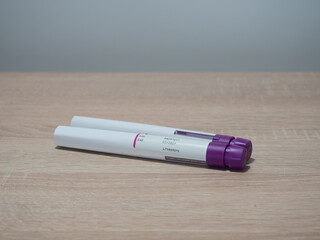Two medical insulin pens on wooden surface