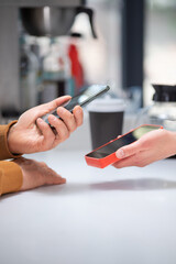 Close-up: a customer makes a purchase in a coffee shop, pays with a QR code. Scans the QR code with a smartphone in the bank's application.