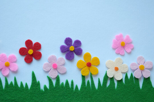 Handmade felt garden, DIY floral craft, colorful fabric flowers, spring meadow theme, creative textile decoration, soft petals, green grass, pastel background, sewing project