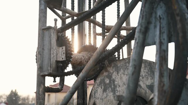 Close-up of gears from a mechanism for drilling wells for water from underground. The sun in the background