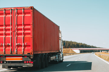 Freight truck transporting red shipping cargo container on road © AlexGo