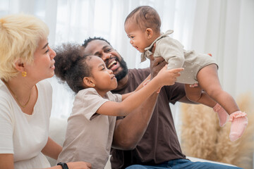Fototapeta premium Joyful family bonding with two young children at home during a sunny afternoon