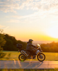 Motorcyclist rides through beautiful sunset landscape.