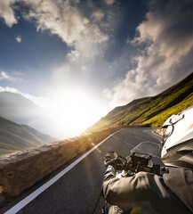 Naklejka premium Detail of motorcycle handlebars. View from driver perspective, beautiful Alpine landscape in sunset light.