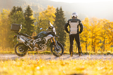 Motorcyclist stays in scenic autumn forest trail.