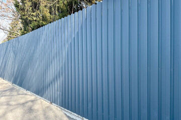 Grey blue modern metal fence made of separate vertical sections for fencing a territory.
