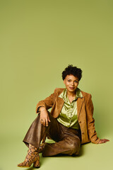 Obraz premium Stylish African American woman showcasing trendy fashion against a vibrant green backdrop