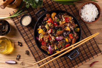 Traditional Asian sweet and sour pork with paprika and sesame. Prepared in a wok.