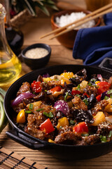 Traditional Asian sweet and sour pork with paprika and sesame. Prepared in a wok.
