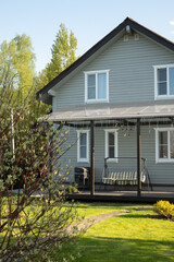 Cottagecore contemporary gray house of wood with patio in countryside. Spring. Russian dacha in Moscow region. Outdoors. Backyard and traditional gardening.