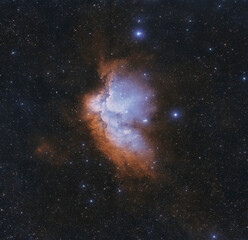 Wizard Nebula (NGC7380). A starry sky with a bright orange cloud in the middle. The cloud is...
