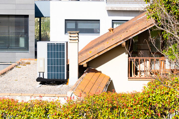 Modern outdoor aerothermal equipment with integrated solar panels for self-sufficiency. On the roof of a house