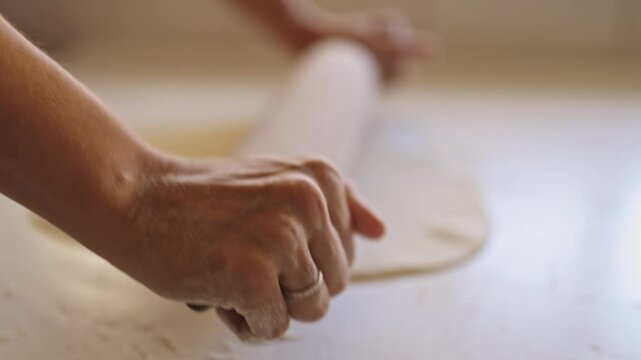 Woman rolling dough for pie crust on white table