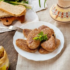 Cutlets on a plate on a wooden background. Fried meatballs with herbs. Home cooking. Meat cutlets with mustard.