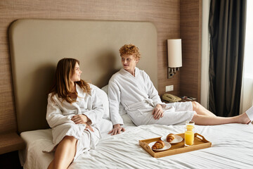 Young couple enjoys a relaxed morning together at a cozy hotel retreat with breakfast in bed