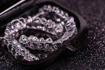 Obraz premium Invisalign transparent aligners rotate in a black container. Plastic removable teeth correction retainers.